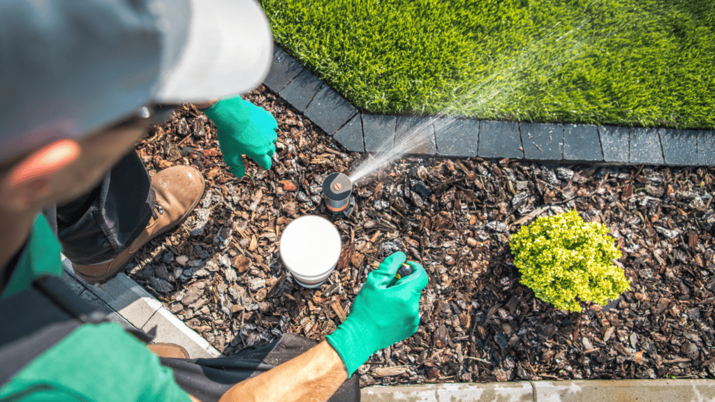 A person wearing gloves adjusts a sprinkler head to ensure proper watering of a lawn, demonstrating the importance of precise irrigation control to avoid overwatering